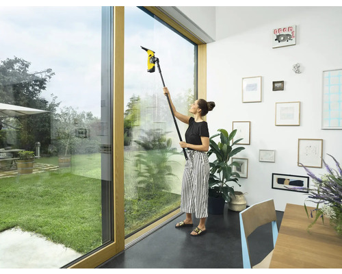 Vrouw reinigt ramen met een raamzuiger binnenshuis.