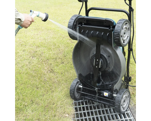 Een gazonwals wordt schoongemaakt met een waterslang.