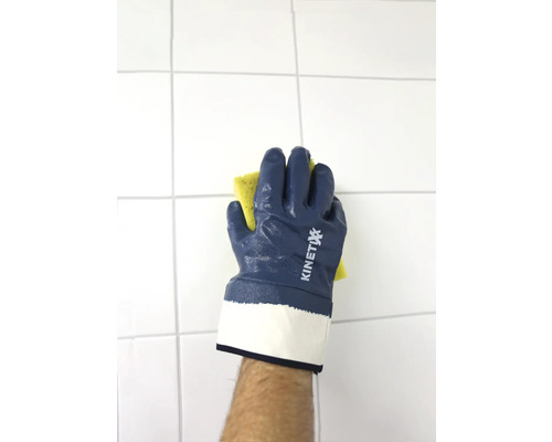 Een hand met KINETIXX werkhandschoen veegt met een spons een betegelde muur af.