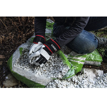 Persoon vult zak met decoratief grind met tuinhandschoenen