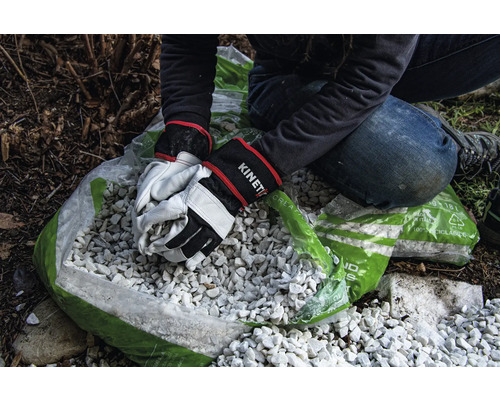 Persoon vult zak met decoratief grind met tuinhandschoenen