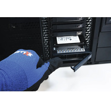 Een persoon met handschoenen installeert een SSD in een computerbehuizing.
