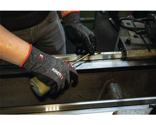 Persoon met KinetiXx werkhandschoenen aan het werk op een machine.