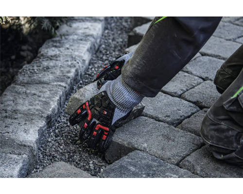 Een persoon legt bestratingsstenen met beschermende handschoenen.