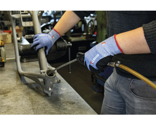 Een man reinigt een fietsframe lager met een gereedschap terwijl hij werkhandschoenen draagt