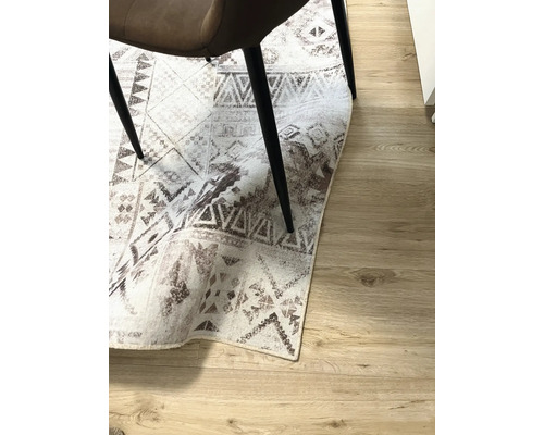 Decoratief tapijt met geometrische patronen onder een stoel op een houten vloer.