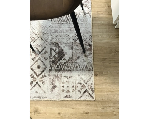 Tapijt met grafisch patroon onder een stoel op een houten vloer.