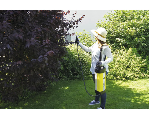 Vrouw gebruikt een tuinspuit voor ongediertebestrijding in de tuin.