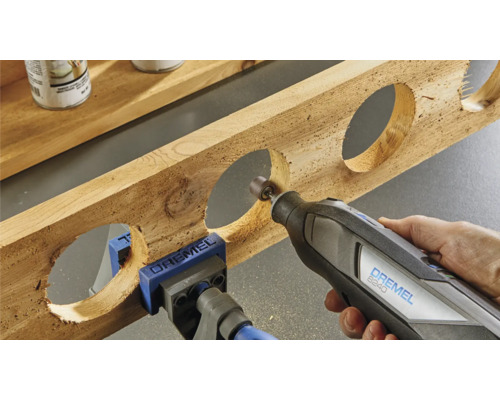 Dremel multifunctioneel gereedschap dat een stuk hout met ronde uitsparingen bewerkt, vastgemaakt met een schroefklem