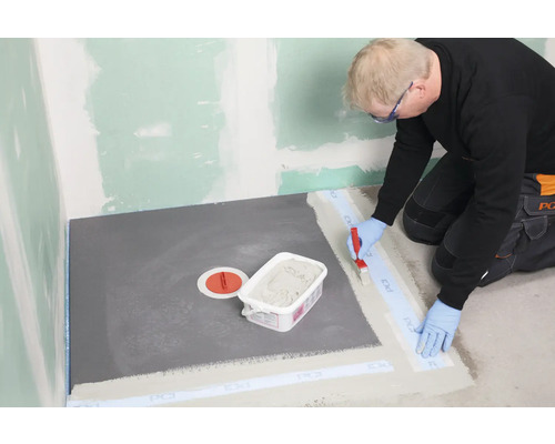 Vakman dicht een douche af met afdichtband en afdichtingsslib