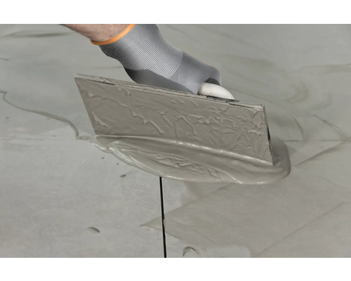 Aanbrengen van voegmortel met een voegrubber op tegels