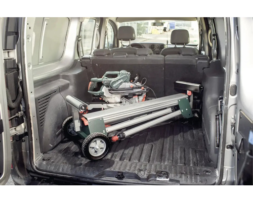 Metabo logo. In de laadruimte van een bestelwagen staat een afkort- en verstekzaag met onderstel.