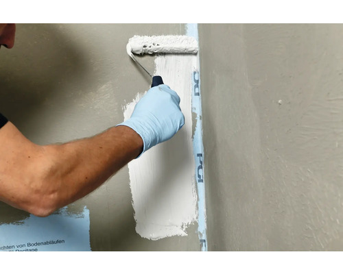 Een persoon brengt met een verfroller een afdichtingsmiddel aan op een muur.