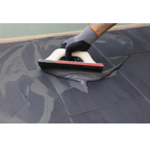 Tegelzetter met spatel bij het voegen van tegels