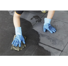 Een persoon maakt tegels schoon met een doek en handschoenen.