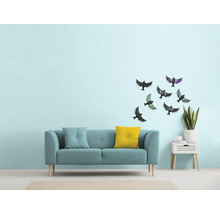 Woonkamer met bank, kussens, wanddecoratie met vogelmotieven en bijzettafel met plant