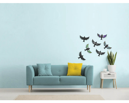 Woonkamer met bank, kussens, wanddecoratie met vogelmotieven en bijzettafel met plant