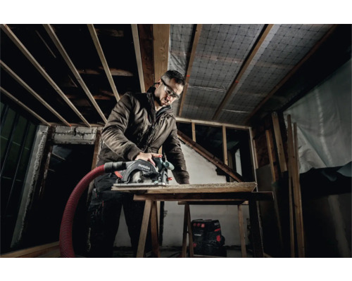 Vakman met veiligheidsbril zaagt hout met een cirkelzaag van Metabo in een casco.
