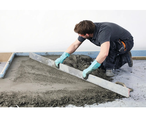 Vakman strijkt dekvloer glad met een afreilat.