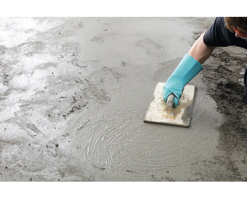 Vakman egaliseert dekvloer met een gladstrijkspaan