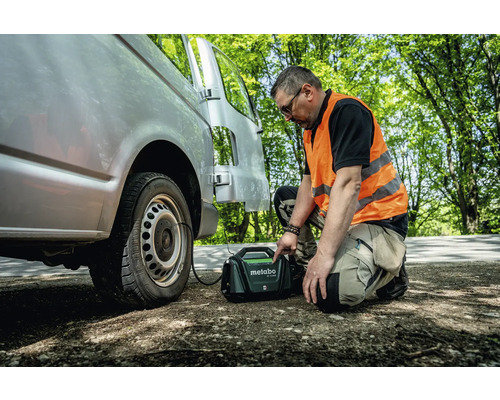 Een man vult een band van een bestelwagen met een mobiele compressor van Metabo.