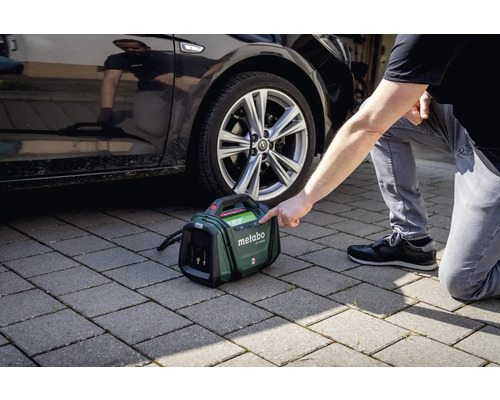 Metabo accukompressor naast een auto op straatstenen