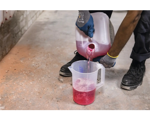 Iemand giet vloeistof uit een container in een maatbeker.