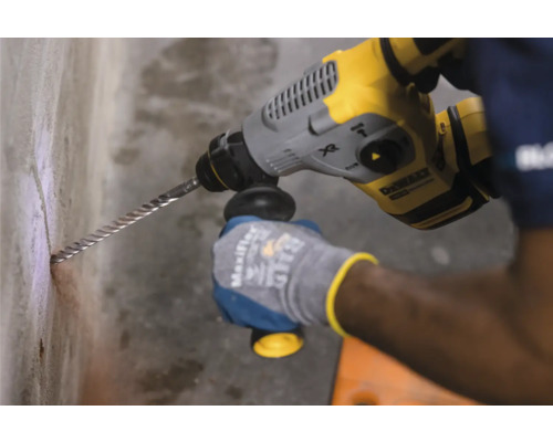 Een persoon boort met een boorhamer een gat in een muur.