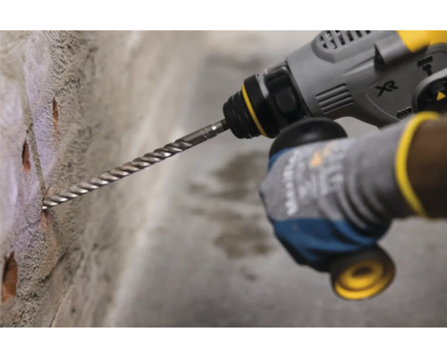 Iemand boort gaten in een bakstenen muur met een boormachine.