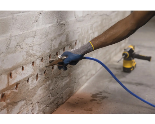 Man injecteert een vloeistof in een muur met een injectieapparaat