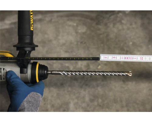 Meting van de boordiepte met een duimstok op een boormachine met boor