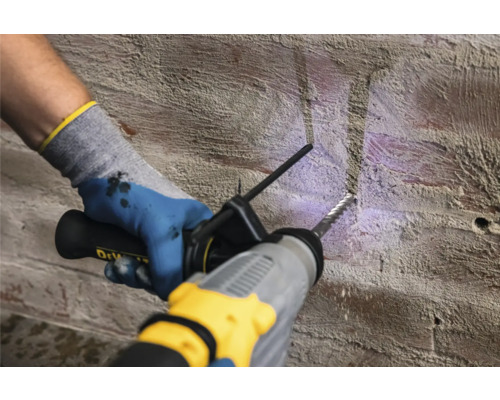 Iemand boort met een boorhamer in een bakstenen muur