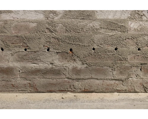 Een bakstenen muur met boorgaten.