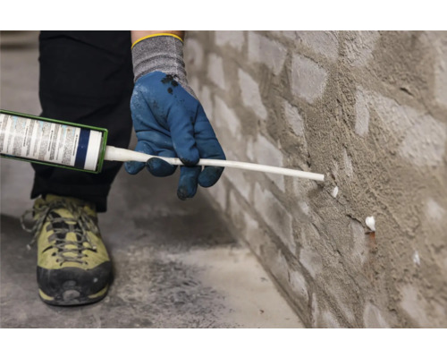 Iemand dicht een bakstenen muur af met kit.