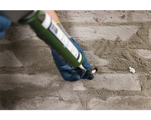 Ambachtsman vult een gat in een stenen muur met kit