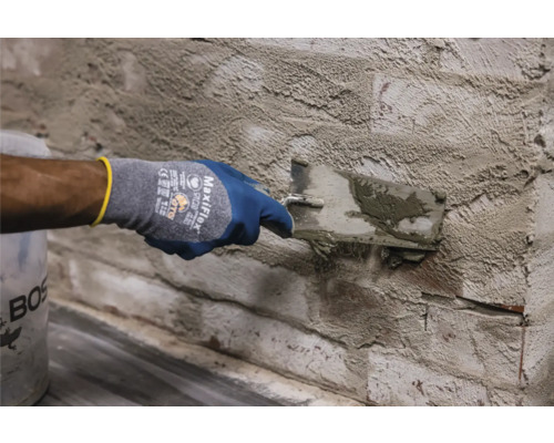 Iemand brengt pleister aan op een bakstenen muur met een troffel