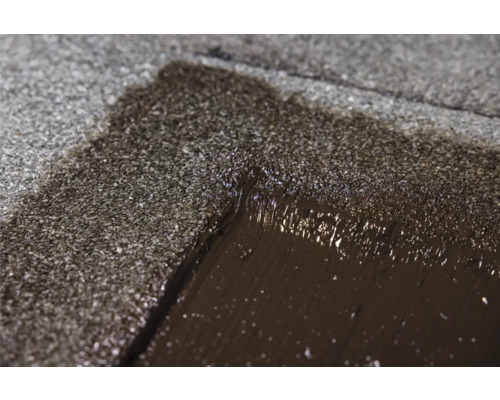 Detailopname van dakreparatie met bitumen coating.