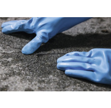 Twee blauwe beschermingshandschoenen liggen op een ruw oppervlak.