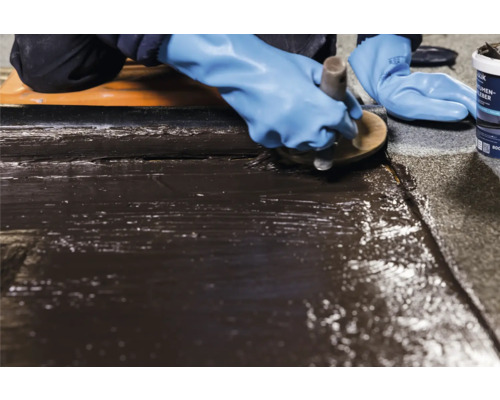 Gebruiker brengt dakleer aan met een bitumenlijm.