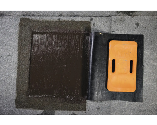 Detailopname van een dakreparatie met bitumen en afdichtband