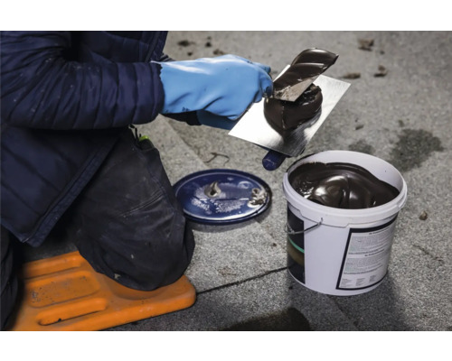 Ambachtsman met spatel en emmer dakbedekkingsmateriaal