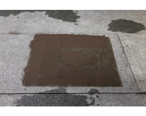 Dakreparatie met bitumen coating op een dakoppervlak.