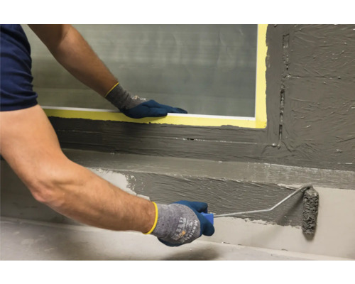 Ambachtsman brengt met een verfroller afdichtende slurry aan op een vensterbank