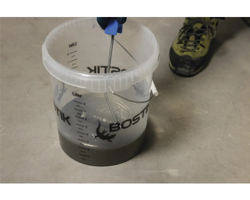 Bostik egalisatiemortel mengen in een emmer