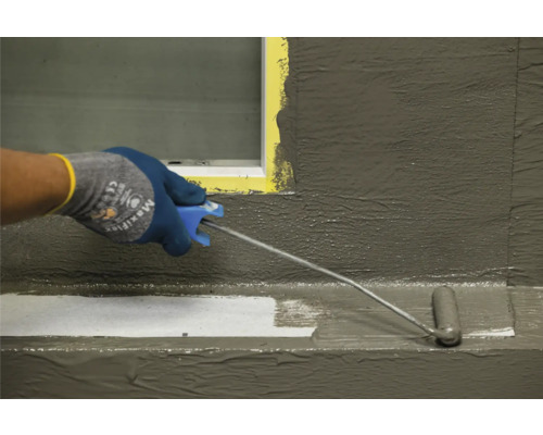 Een persoon brengt met een verfroller een beschermlaag aan op een oppervlak