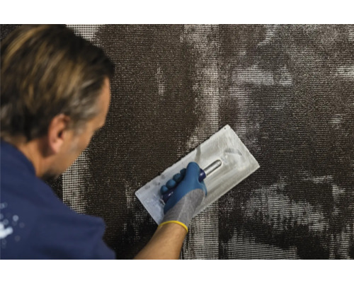 Man brengt wapeningsmortel aan op een weefsel met een pleisterspaan.