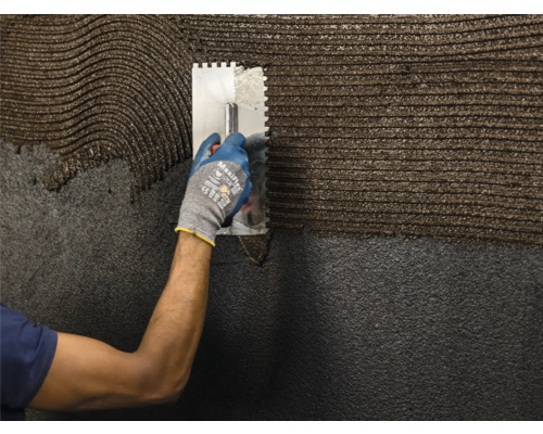 Een persoon brengt met een spaan lijm aan op een oppervlak