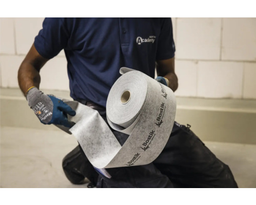 Een persoon rolt een rol Bostik-isolatieonderlaag uit
