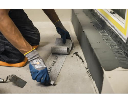 Een persoon installeert afdichtband voor waterdichting binnenshuis.