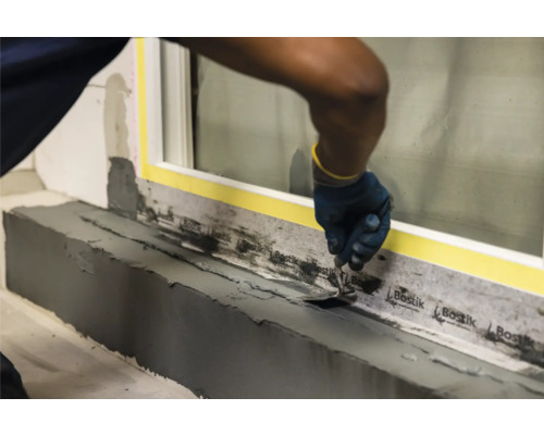 Persoon brengt afdichtmiddel rond een raam aan